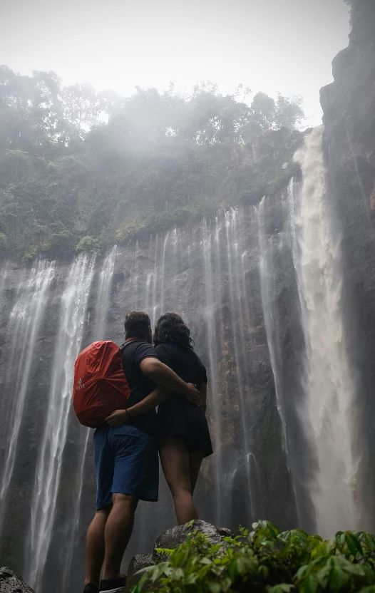 Two individuals standing beneath a waterfall during an outdoor journey, representing healing, renewal, and the path toward recovery.